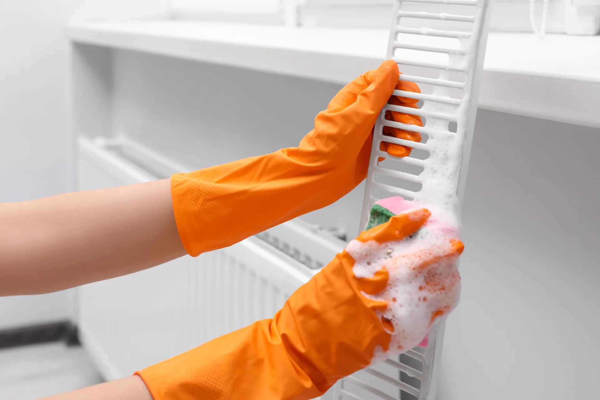Scrubbing between the fins of a radiator with a soapy sponge