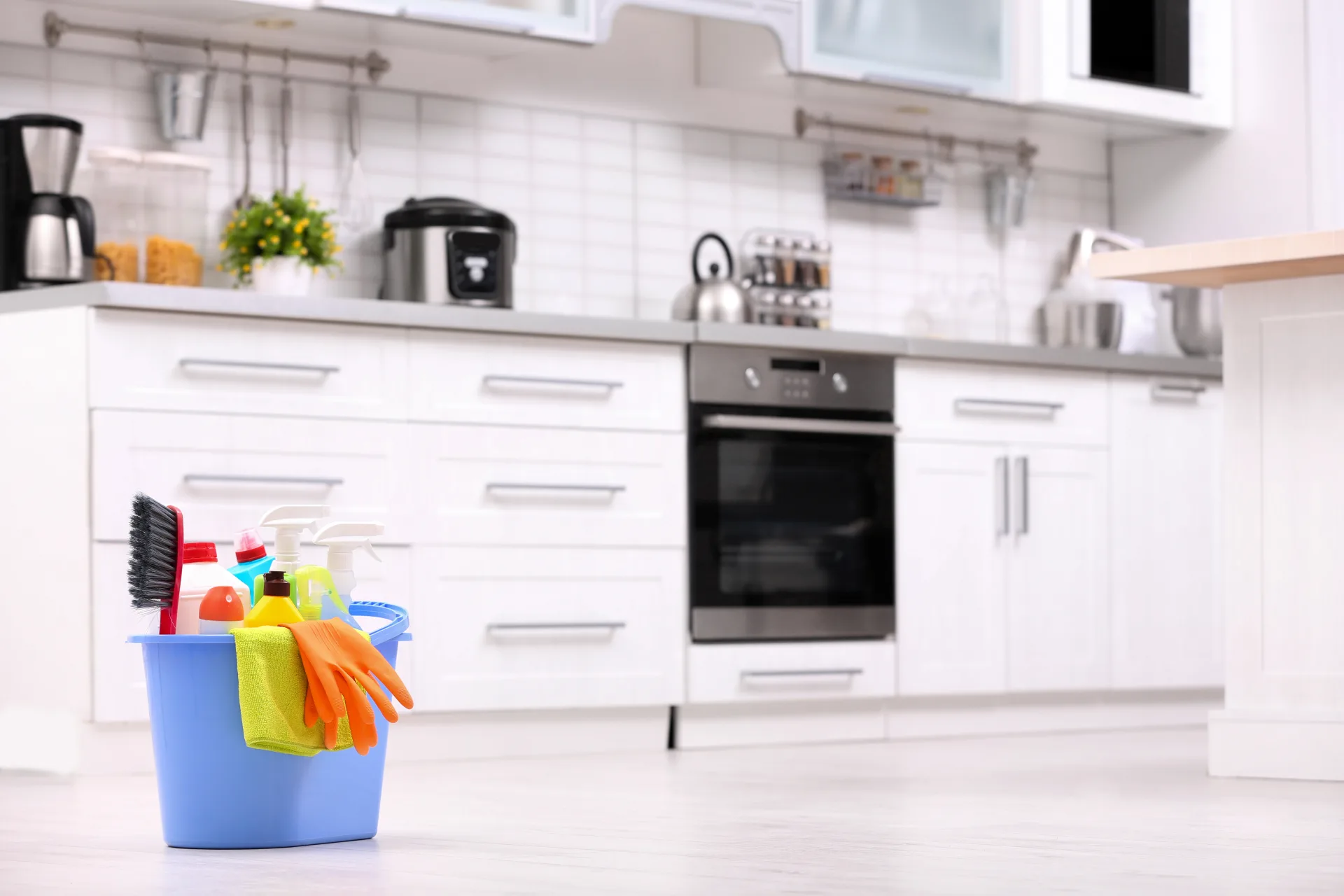A bucket of cleaning supplies and gloves on a kitchen floor