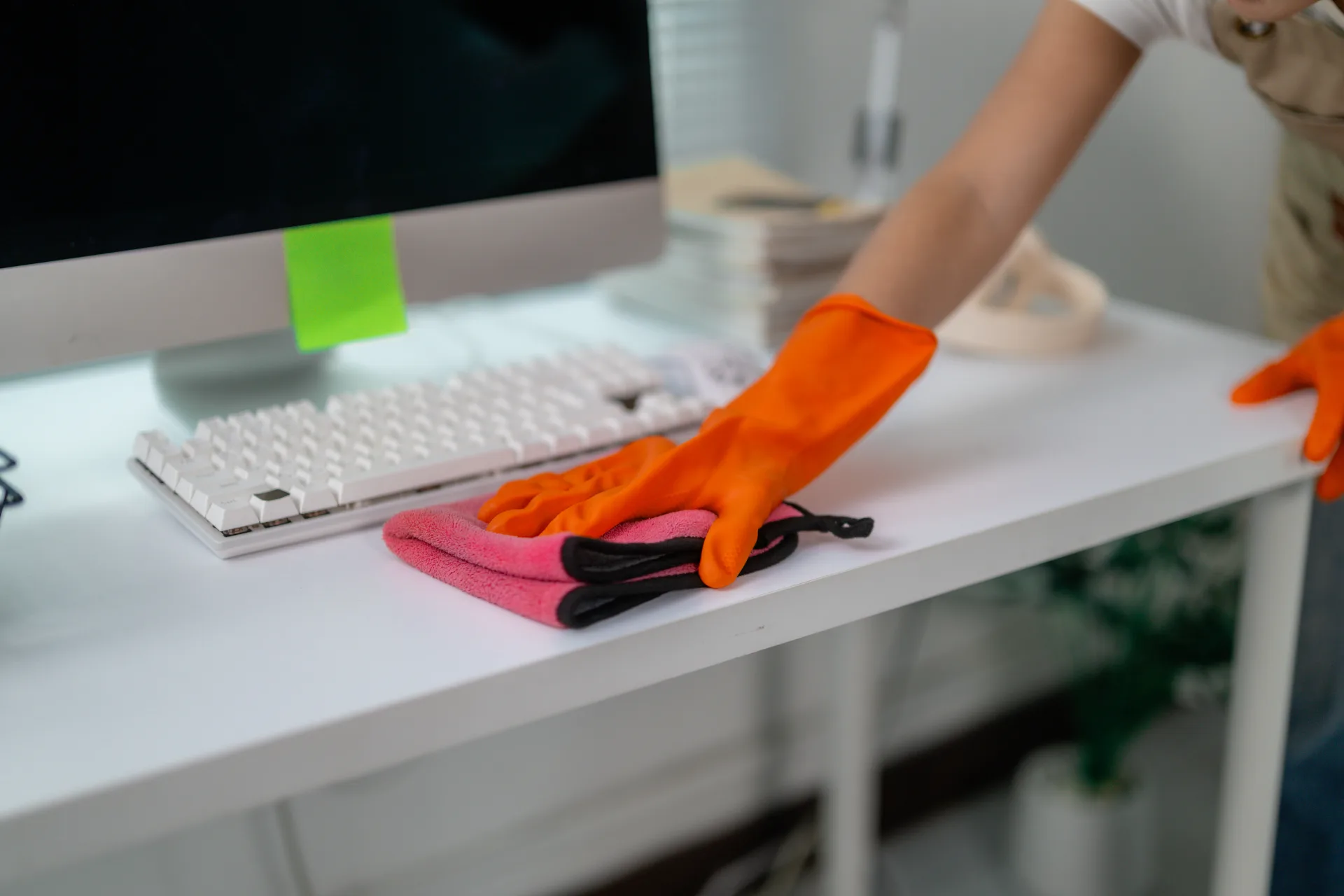 Wiping down a desk and keyboard with a cloth