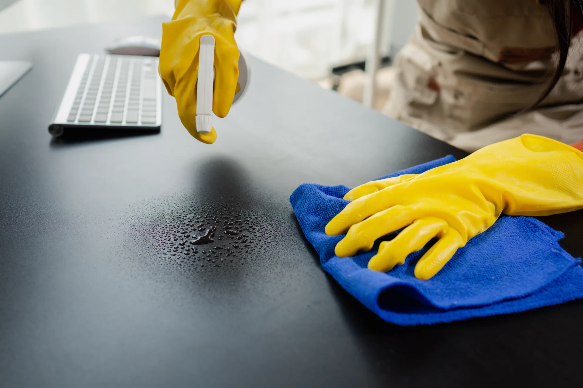 Spraying and wiping a dark worktop with a microfibre cloth